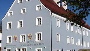 A multi-story building with a grey facade and red roof, featuring several windows and a sign indicating it is a hotel. - Hotel Schwarzacher Hof (Schwarzach)