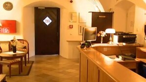 A hotel room with a wooden desk, a chair, a small table with a pineapple, a lamp, a computer, and a view of the hallway. - Hotel Schwarzacher Hof (Schwarzach)