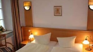 A hotel room with two beds, nightstands, and wall-mounted lamps. - Hotel Schwarzacher Hof (Schwarzach)