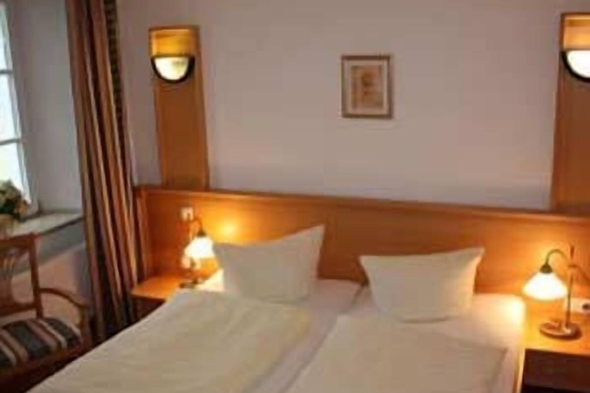 Ett hotellrum med två sängar, sängbord och väggmonterade lampor.
