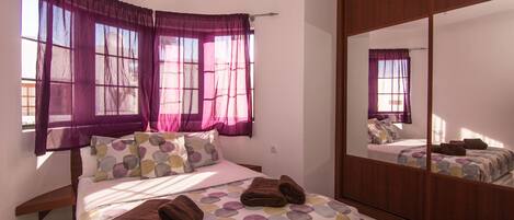A bedroom with a bed, a wardrobe, and a large mirror.