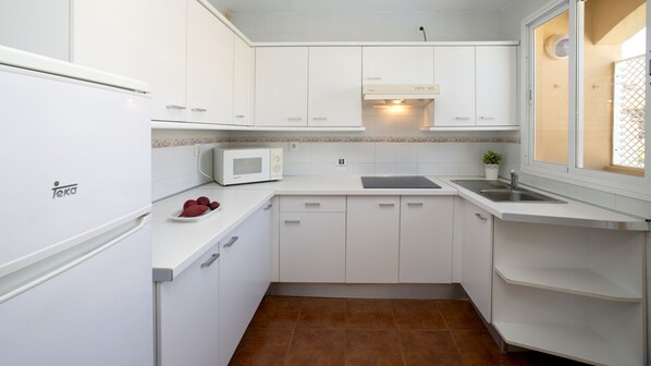 A compact kitchen with white cabinets, a microwave, and a sink.