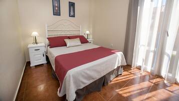 Un dormitorio ordenado con cama, mesitas de noche y ventana con cortinas.