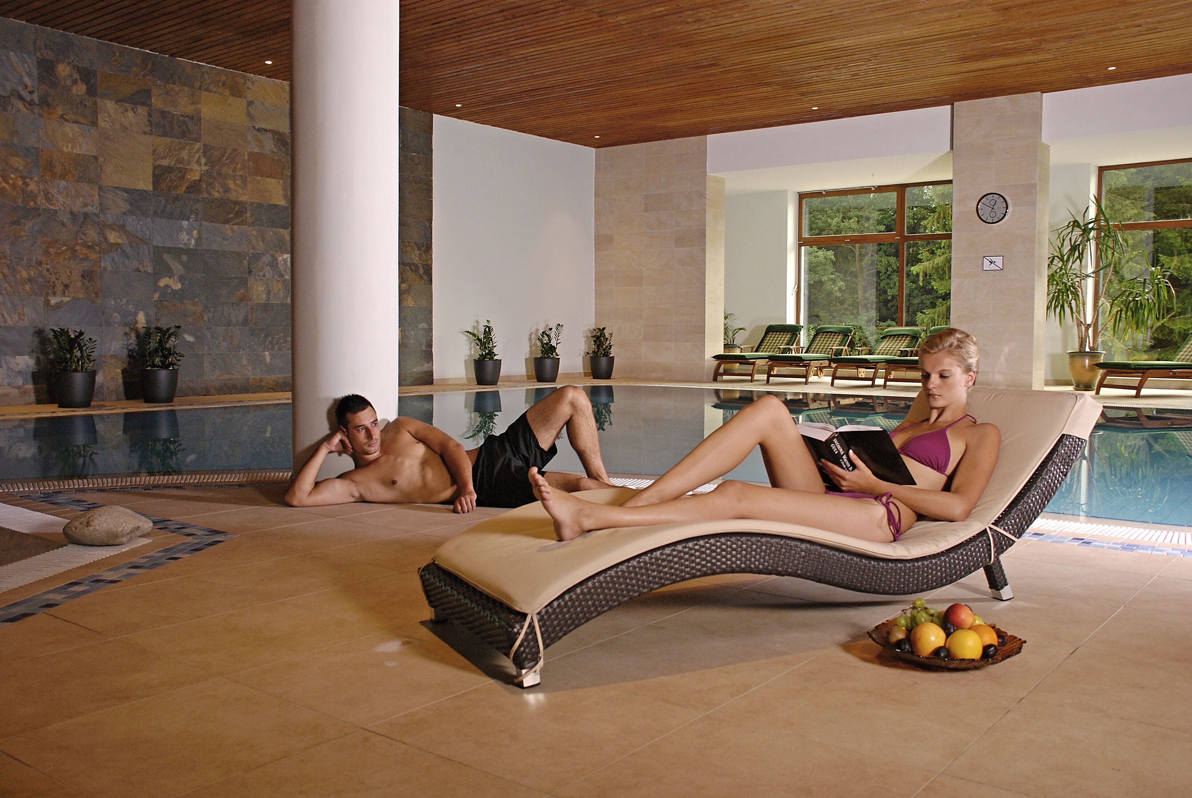 A poolside lounge area with reclining chairs, a pool, and potted plants.