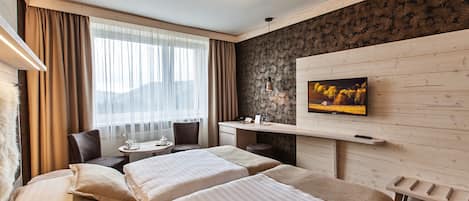 Habitación de hotel con dos camas, un televisor en la pared, un escritorio con una silla y una ventana con cortinas.