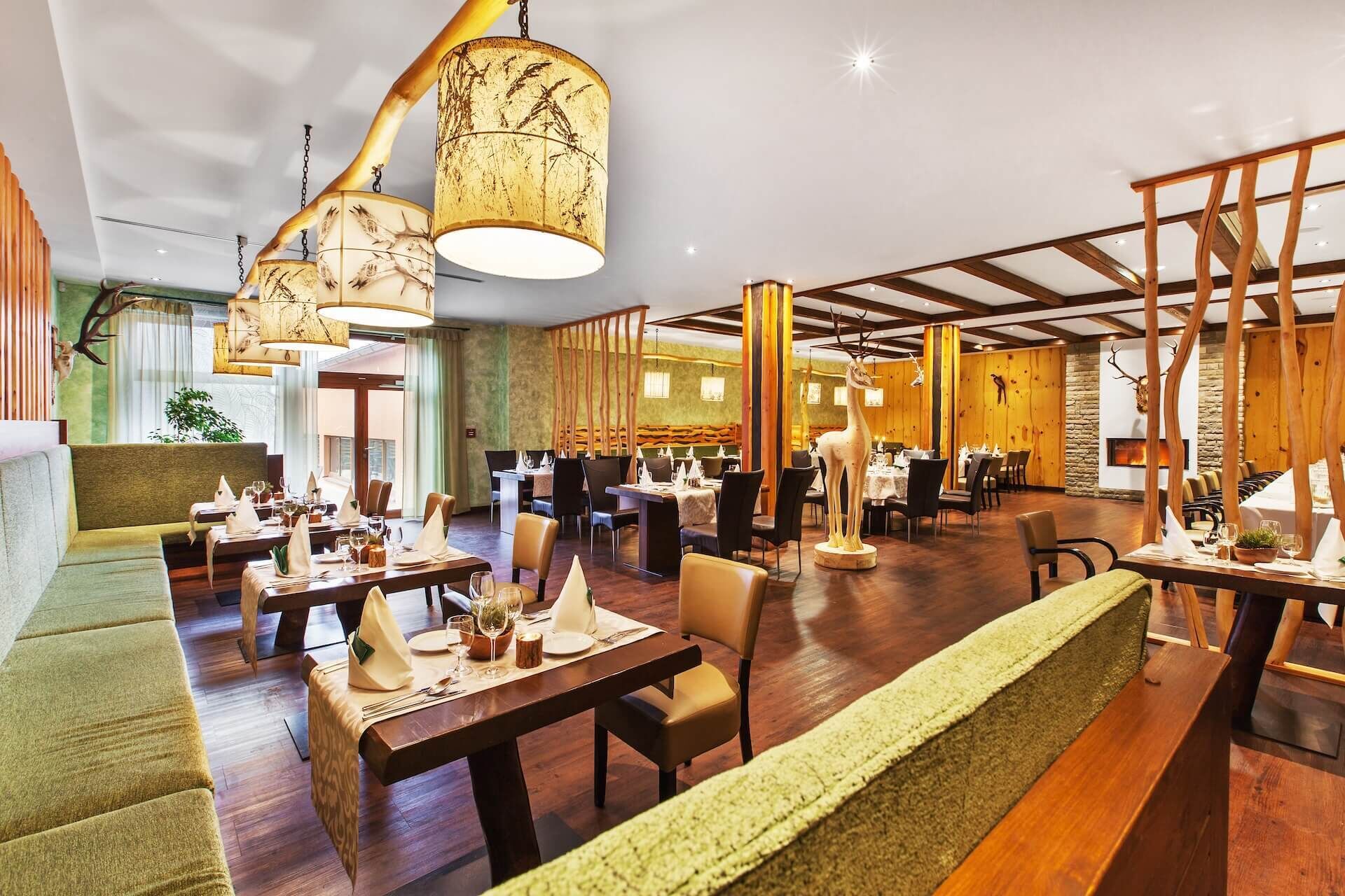 A restaurant with wooden beams, tables set with white tablecloths, and a large deer statue.