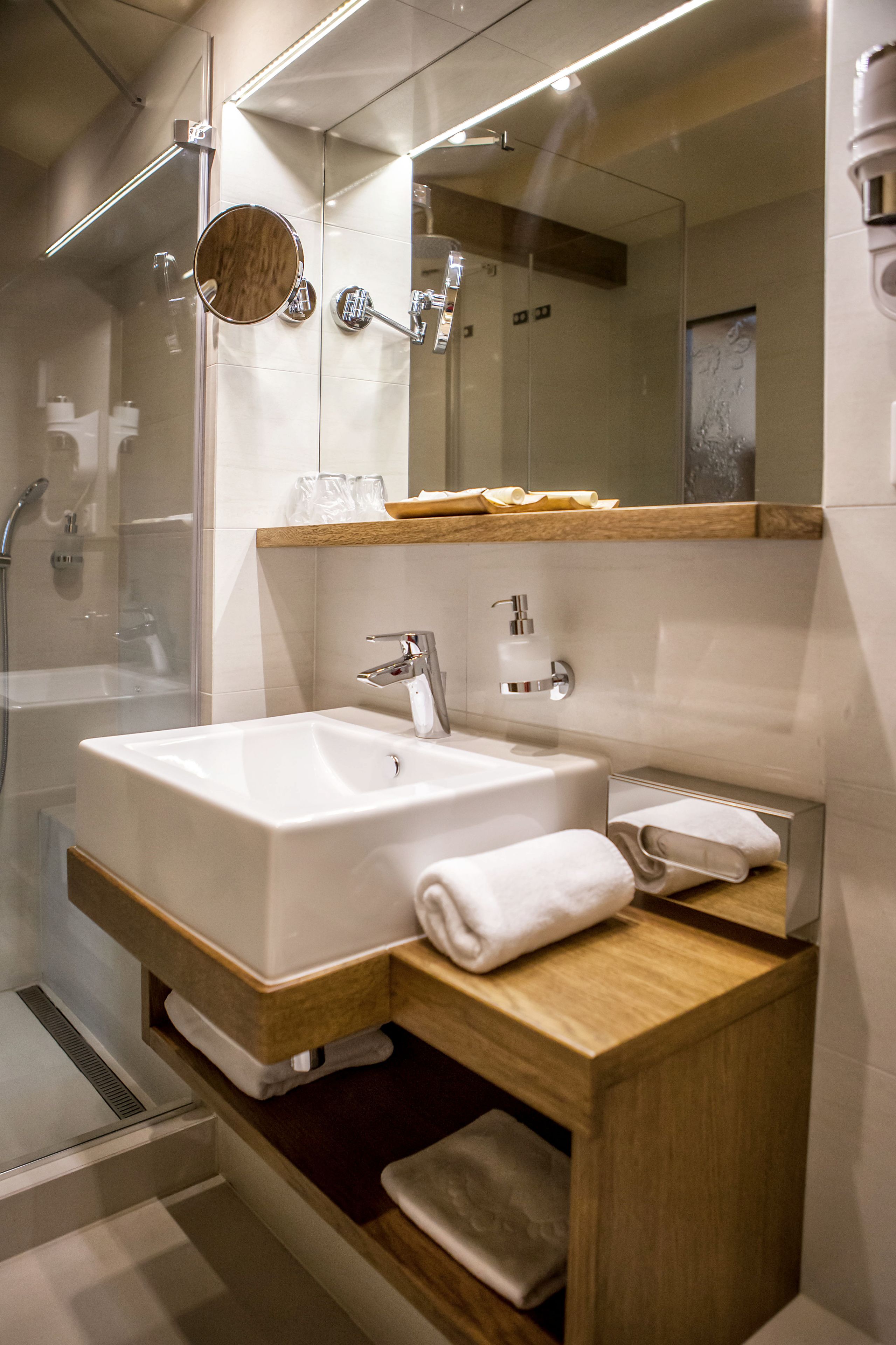 A modern bathroom with a large sink, mirror, and shower.