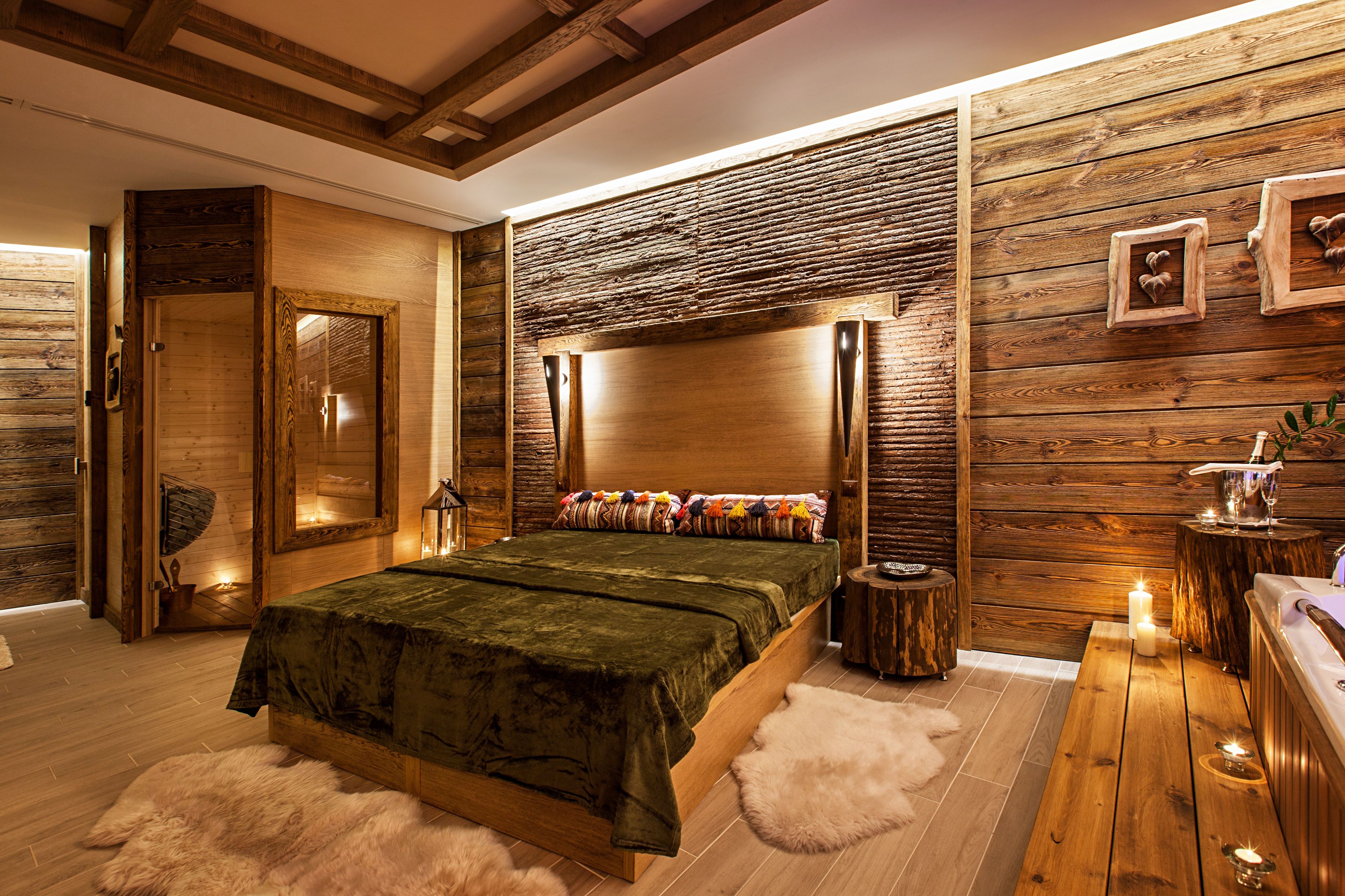 A wooden-themed bedroom with a large bed, a wooden headboard, and a small bedside table with a candle.