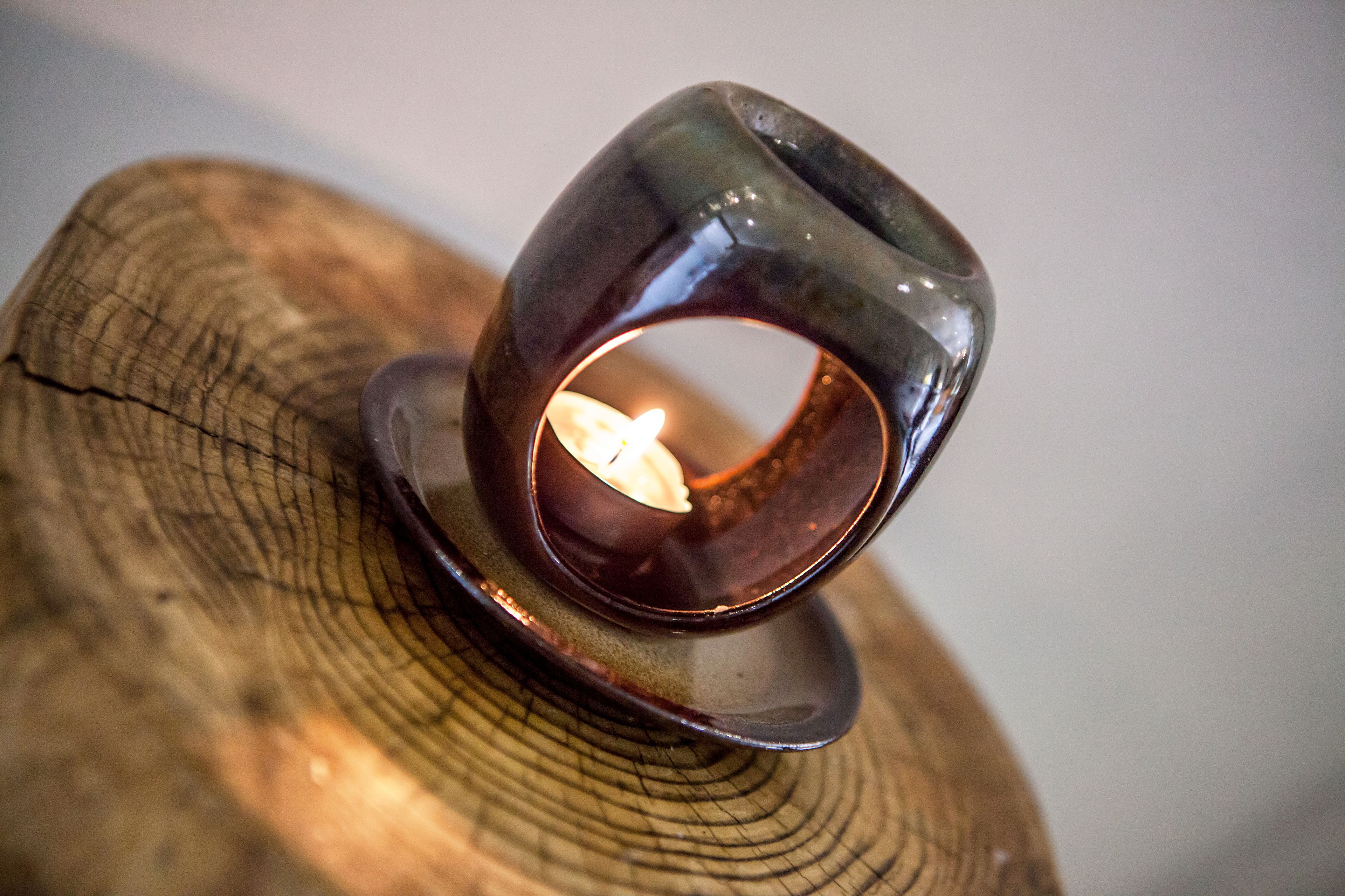 A candle holder with a lit candle on a wooden surface.
