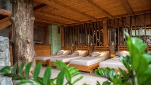 A wooden cabin with four beds, stone walls, and a large tree trunk.