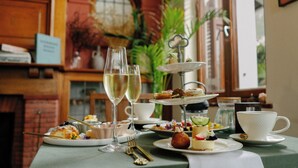 Een gedekte tafel voor een maaltijd met diverse gerechten, een glas witte wijn en een etagère met desserts.