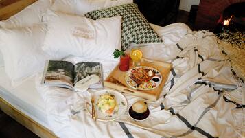 A neatly made bed with a book, a tray with breakfast items, and a cup of coffee.