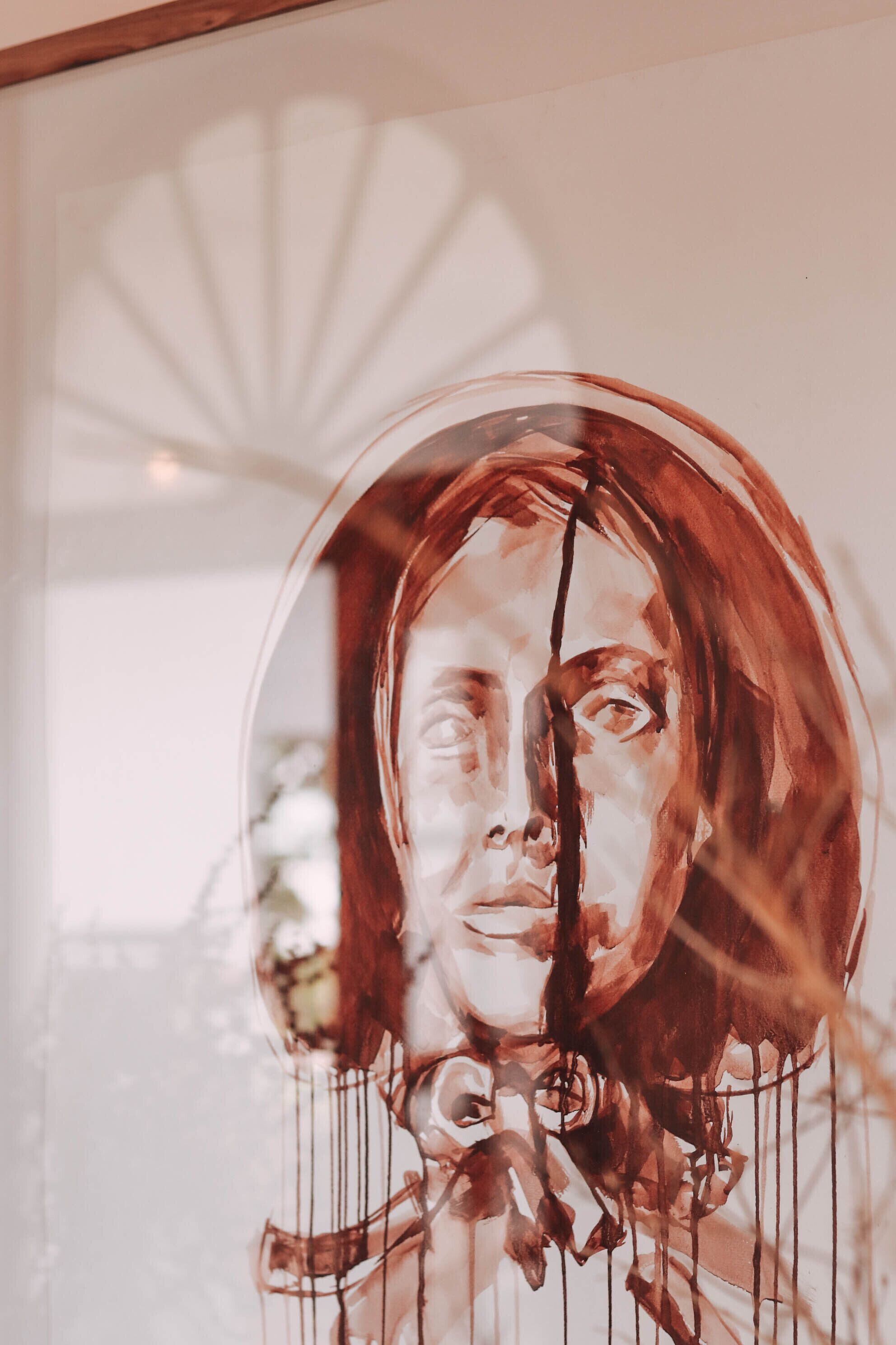 A framed artwork with a circular motif, possibly a portrait, hanging on a wall.
