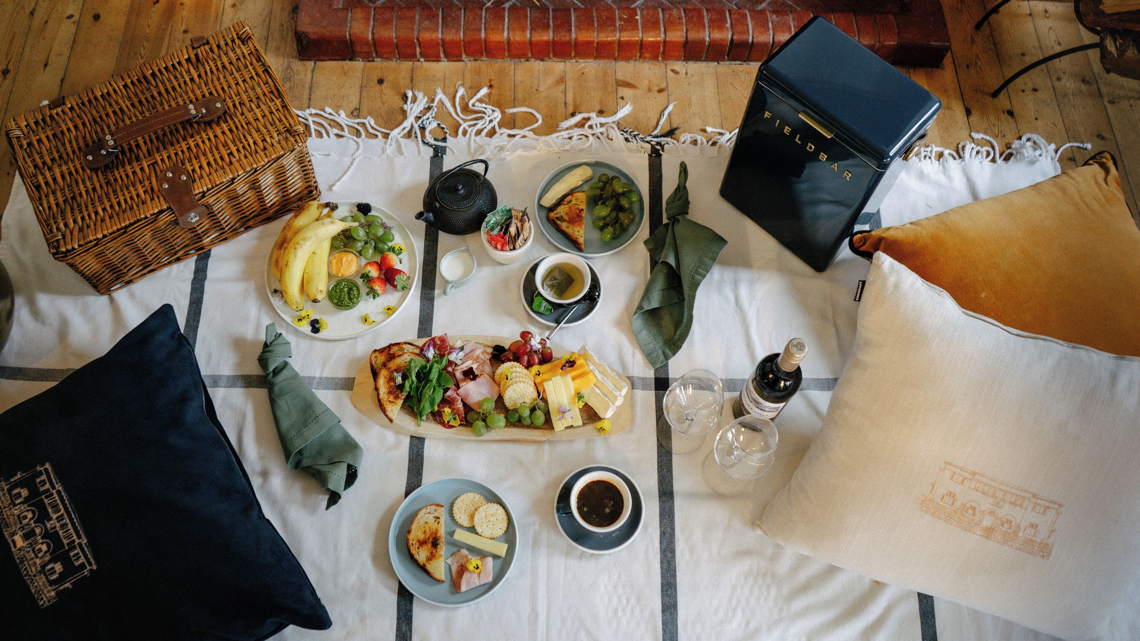 A table set with a variety of food items, including fruits, cheeses, and meats, along with condiments and drinks.