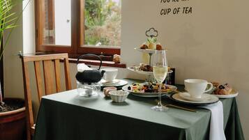 A table set for tea with a tiered dessert display, a teapot, cups, and a wall sign.