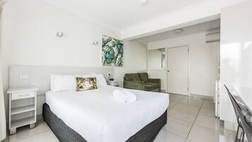 Una camera d'albergo moderna con un letto grande, un comodino, una poltrona verde e una scrivania.