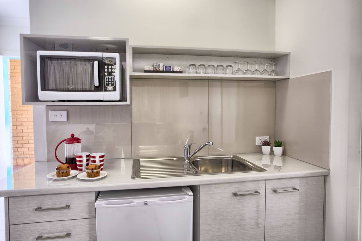 A compact kitchen with a microwave, sink, and a coffee maker.