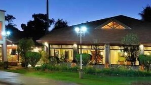 A two-story house with a sloped roof, a front porch, and a well-lit entrance. - Orquideas Hotel & Cabañas (Puerto Iguazú)