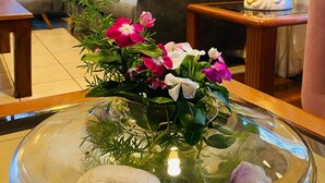 A hotel lobby with a sofa, a table with a vase of flowers, and a decorative lamp. - Orquideas Hotel & Cabañas (Puerto Iguazú)