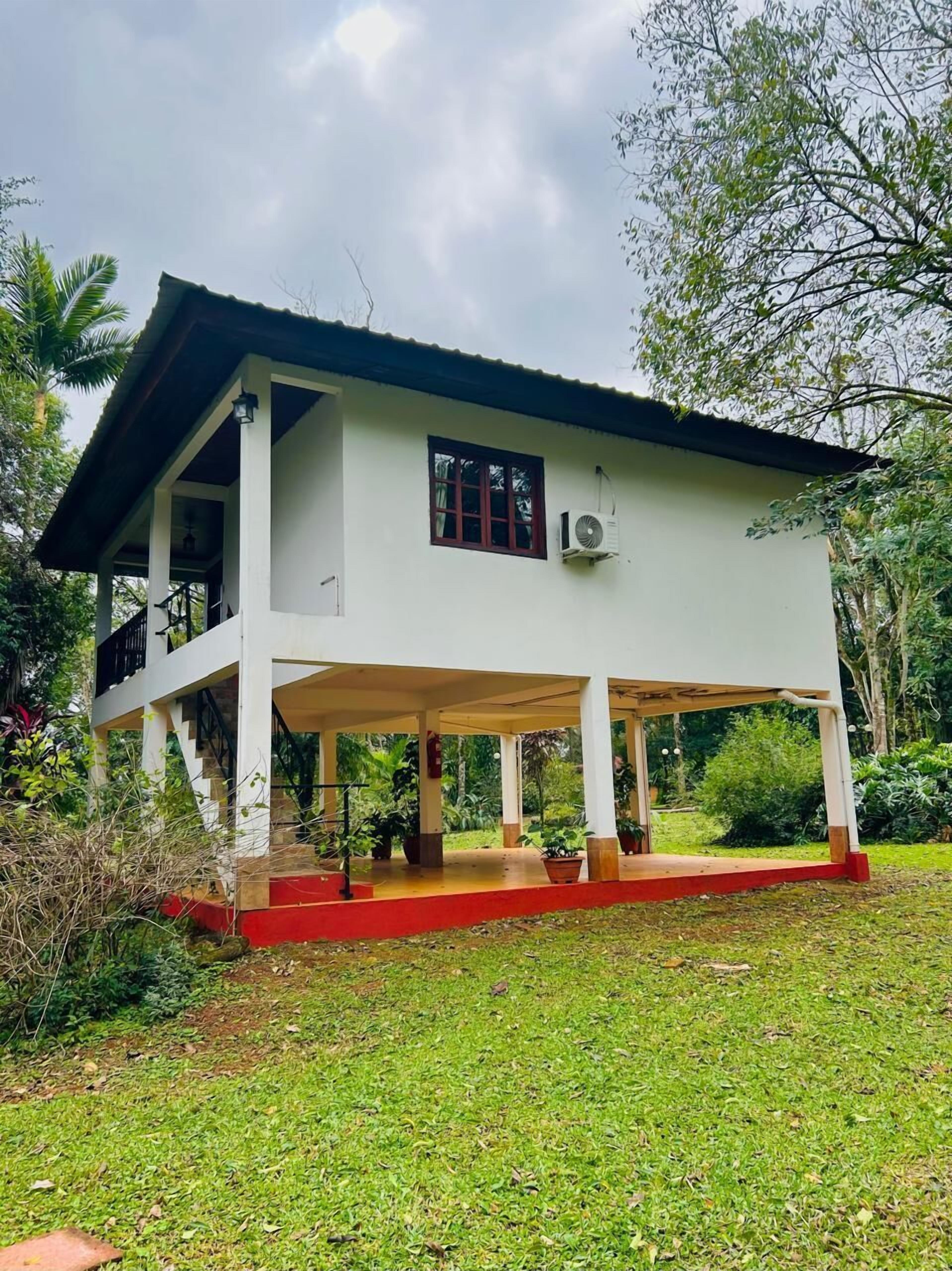 A two-story house with a covered porch, a staircase, and a red base.