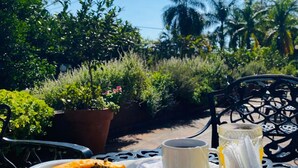 A table with croissants, fruit, and a cup of coffee, set outdoors with a view of greenery and a logo for 'Orgúndias Hotel & Cabanas'. - Orquideas Hotel & Cabañas (Puerto Iguazú)