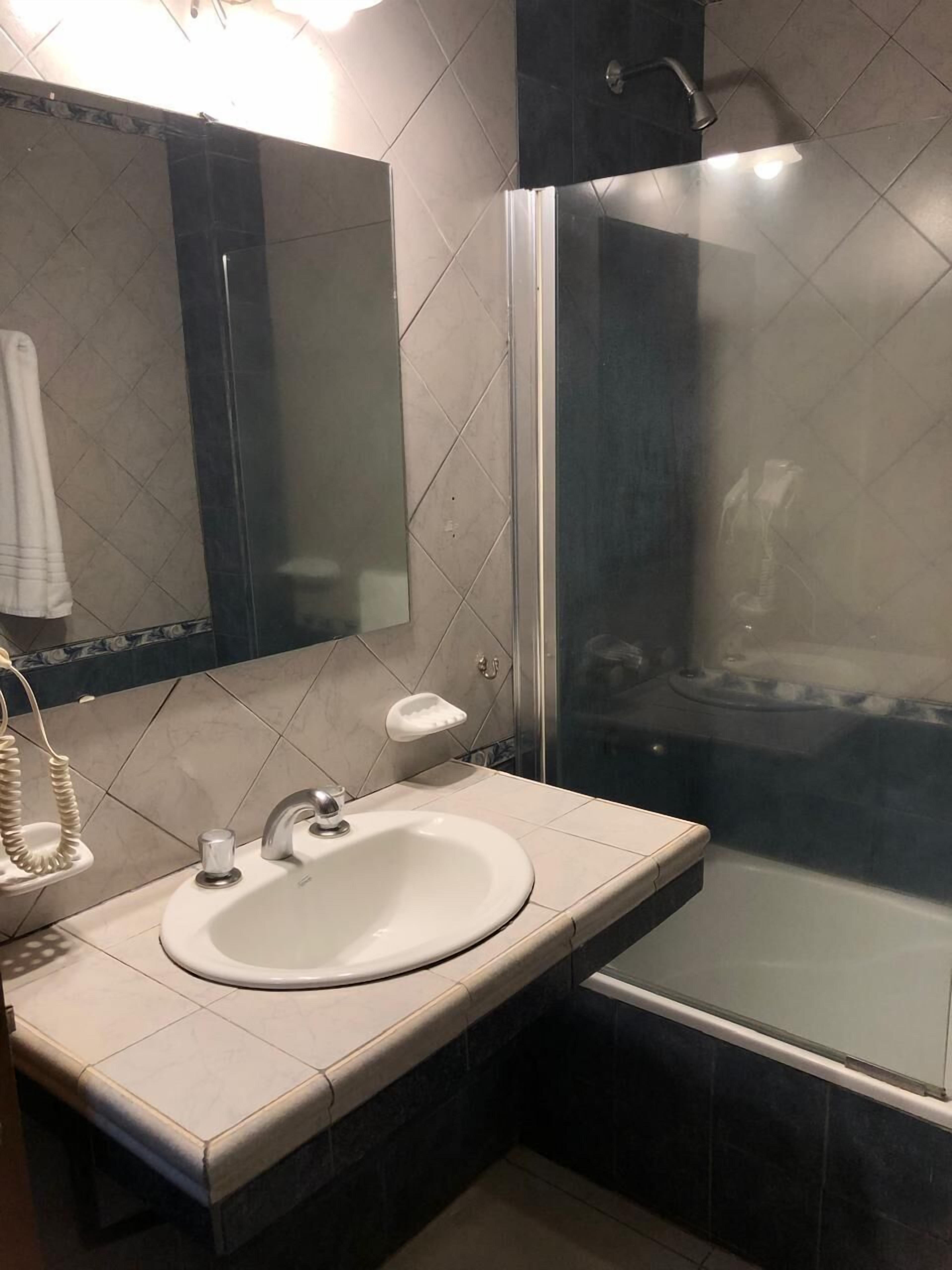 Une salle de bain avec un lavabo, un miroir et une douche.