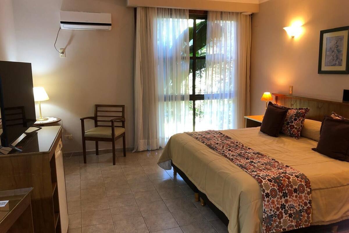 Ein Hotelzimmer mit Bett, Schreibtisch, Stuhl und Fernseher.