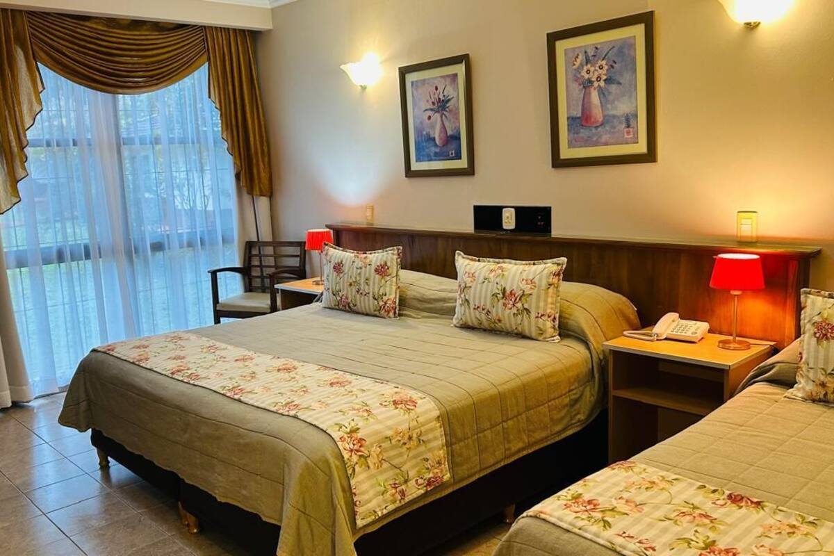 Ein Hotelzimmer mit einem großen Bett, zwei Nachttischen mit Lampen, einem Sessel und einem Schreibtisch.
