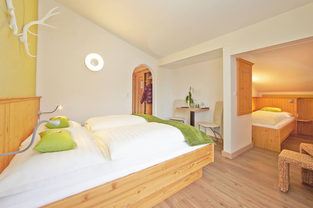 Ein Schlafzimmer mit einem hölzernen Bett, einem Schreibtisch und einer kleinen Sitzecke.