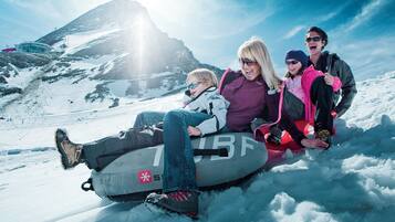 A group of people on a snow tube in a snowy mountainous area.