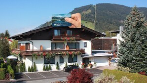 A two-story building with a balcony, a parking lot, and a mountainous backdrop.