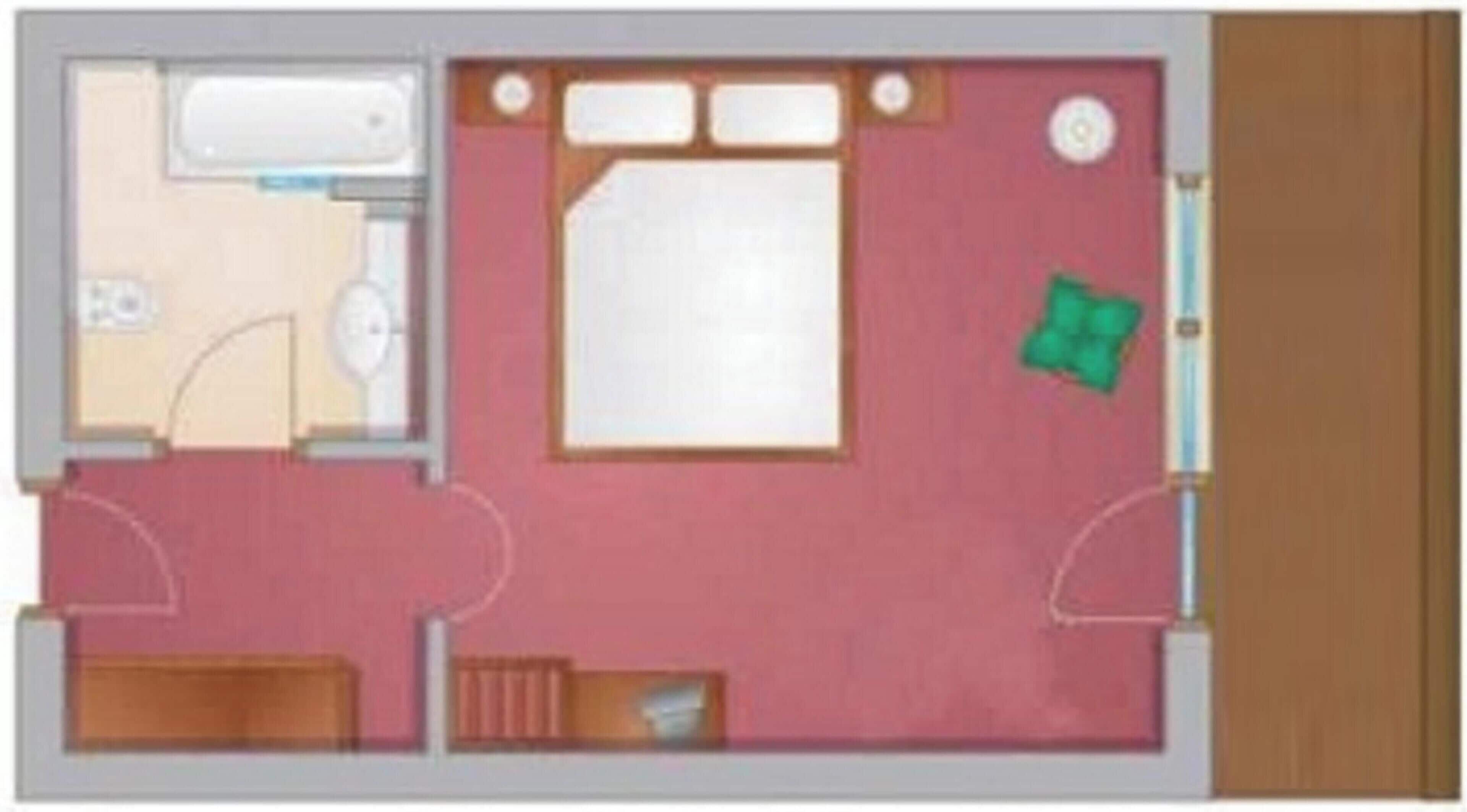 Ein Zimmer mit einem Bett, einem kleinen Schreibtisch, einem Stuhl, einer Toilette und einer Dusche.