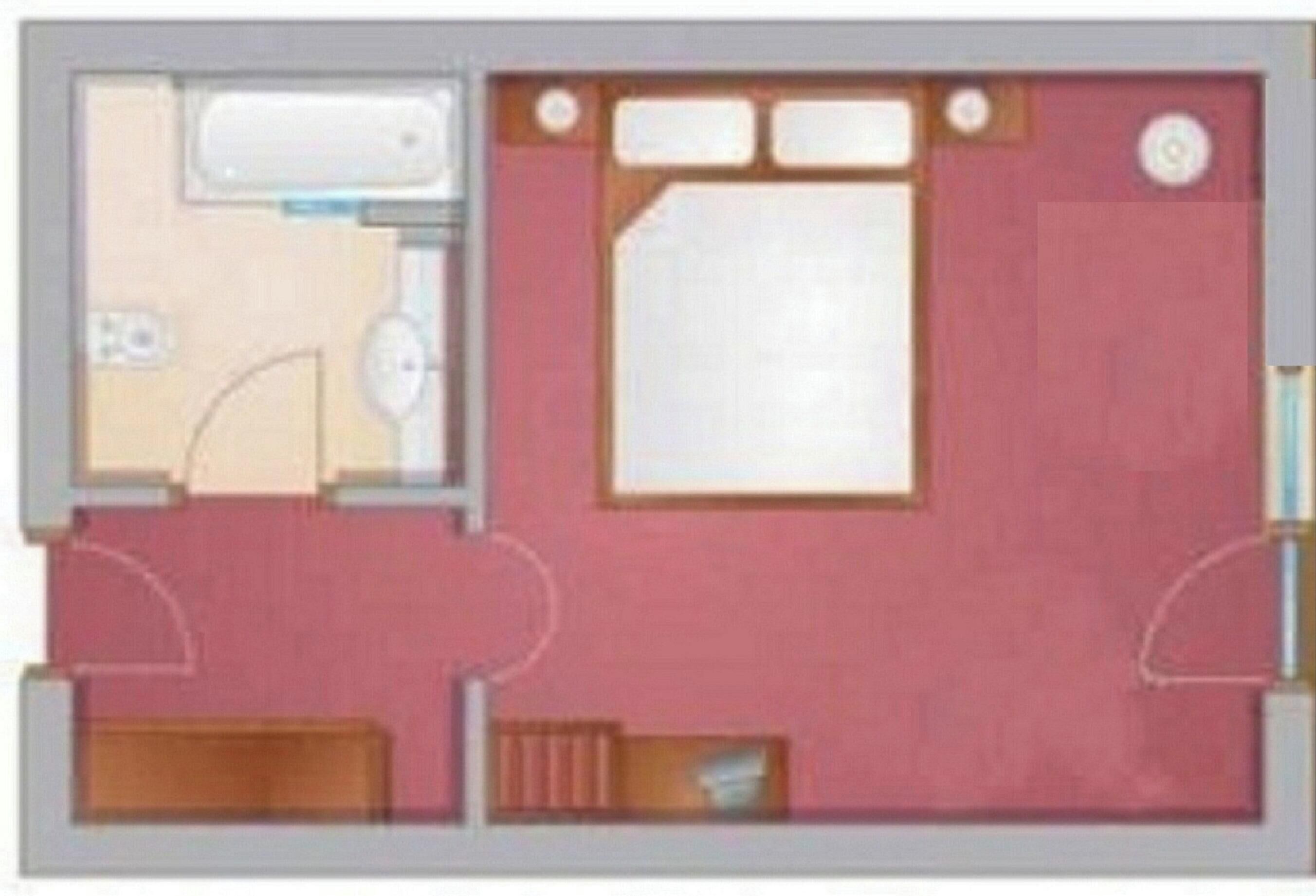 A floor plan of a hotel room with a bed, a bathroom, a small seating area, and a kitchenette.