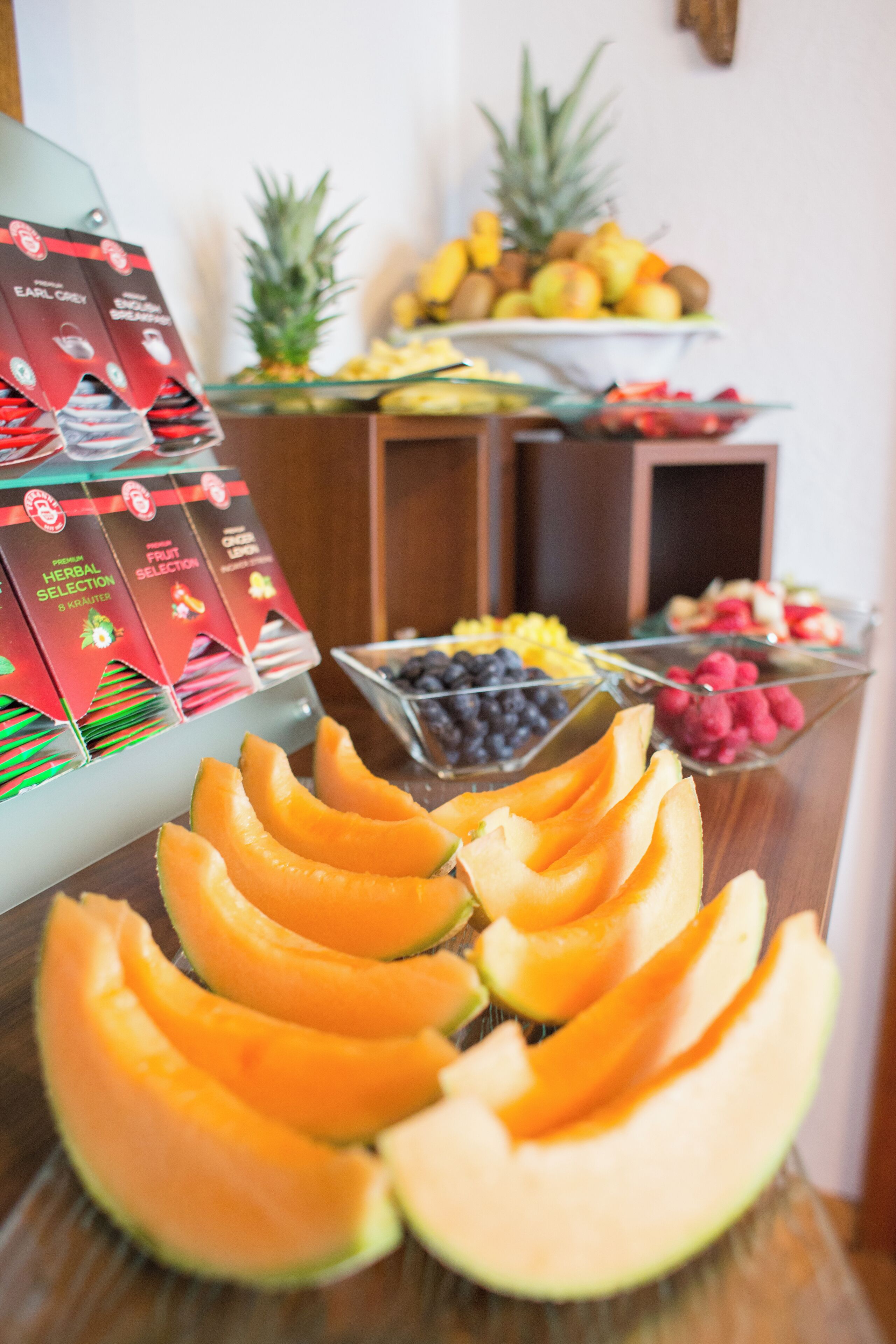 Un bufé con diversas frutas y una selección de cajas de té de hierbas.