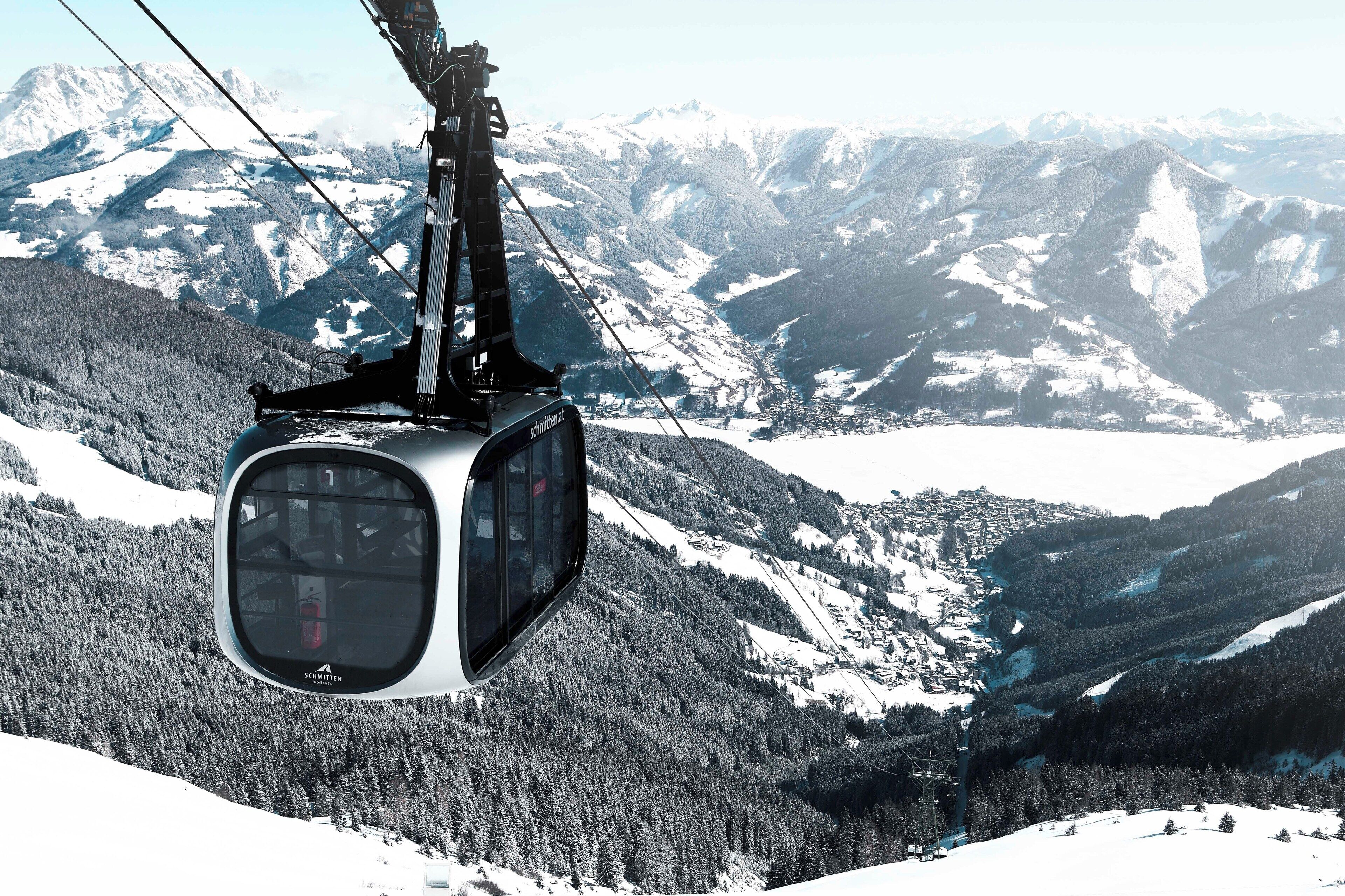 Eine Seilbahn bietet einen klaren Blick auf schneebedeckte Berge und das darunterliegende Tal.