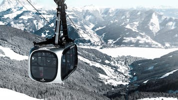 Eine Seilbahn bietet einen klaren Blick auf schneebedeckte Berge und das darunterliegende Tal.