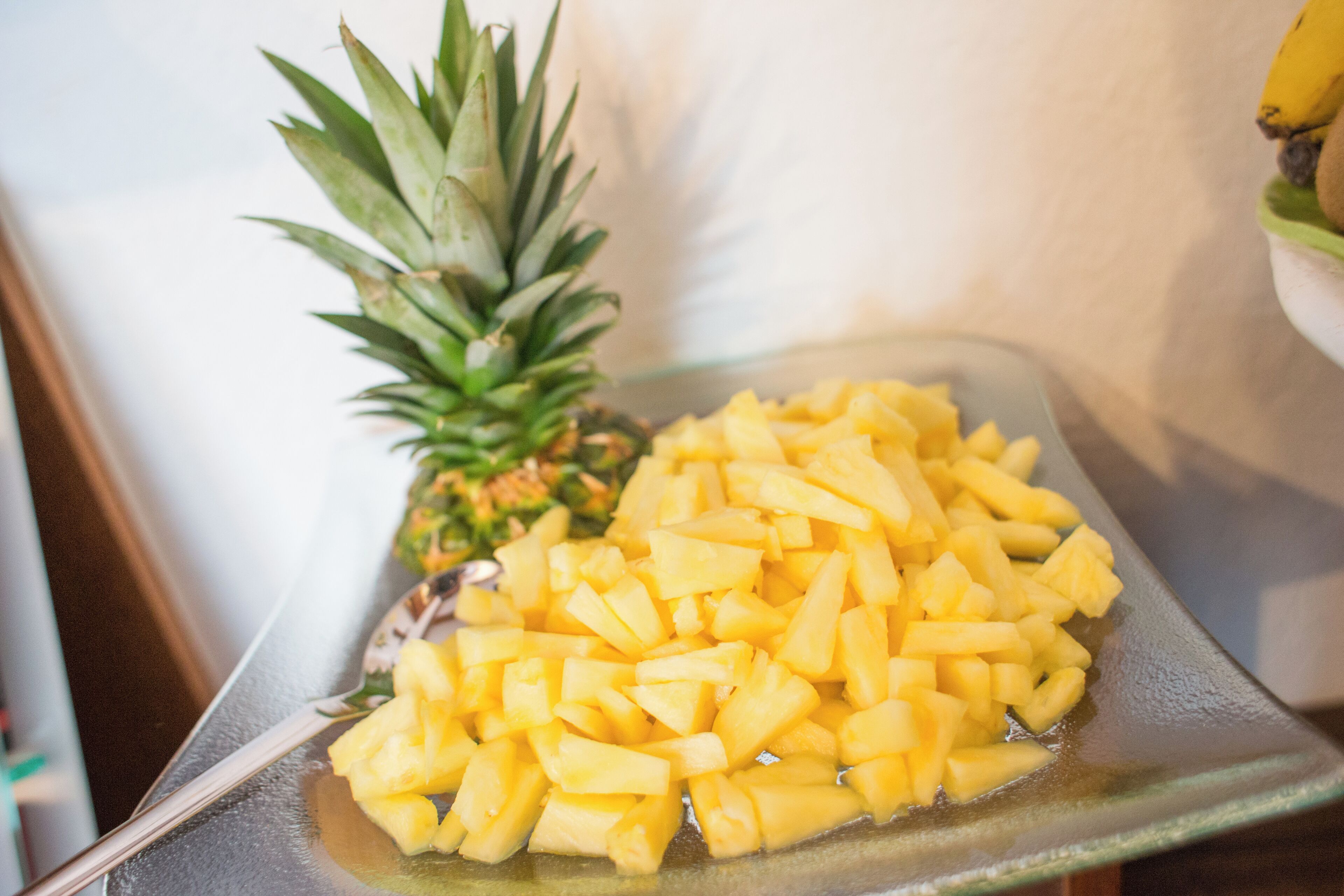 Eine Glasplatte mit gewürfelter Ananas und einer ganzen Ananas.