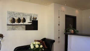 Una sala de estar moderna con un sofá de cuero negro, una mesa de centro con un florero y un cuadro en la pared.