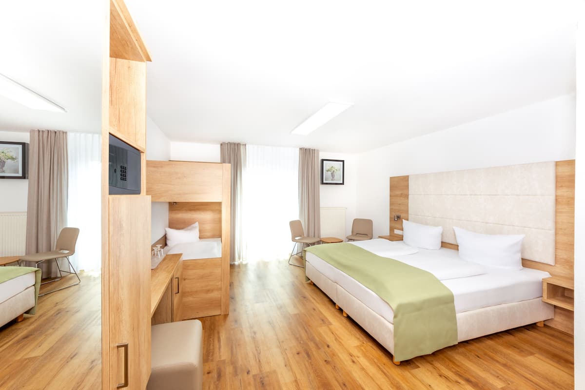 Quarto de hotel com uma cama grande, uma escrivaninha, uma cadeira e uma mesinha.