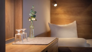 Una mesita de noche de madera con un jarrón de flores blancas y dos candelabros de cristal.