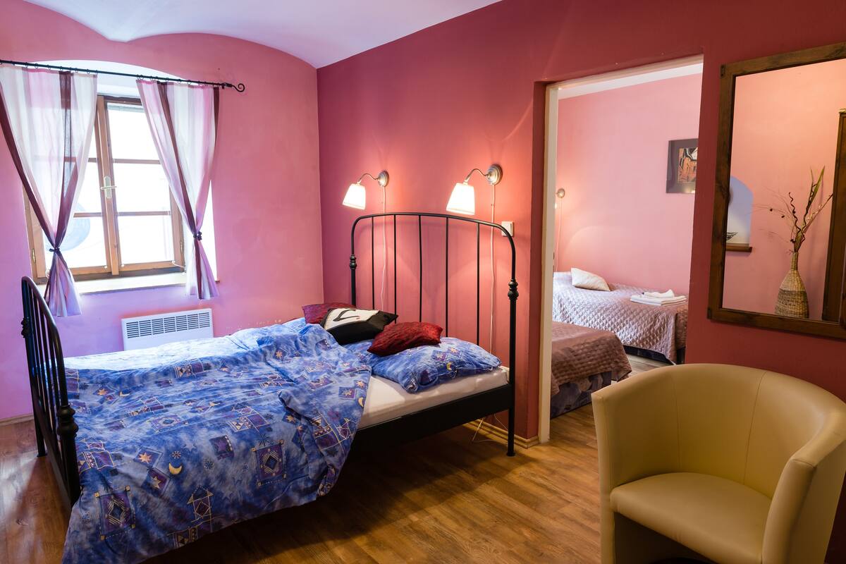 A bedroom with a single bed, a chair, and a window with curtains.