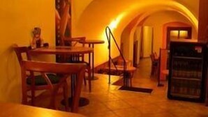 A restaurant interior with wooden tables and chairs, a tiled floor, and a wall-mounted poster. - Pension Marie (Cesky Krumlov)