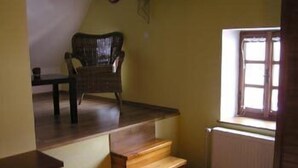 A room with a wooden staircase, a wicker chair, and a window with a view. - Pension Marie (Cesky Krumlov)