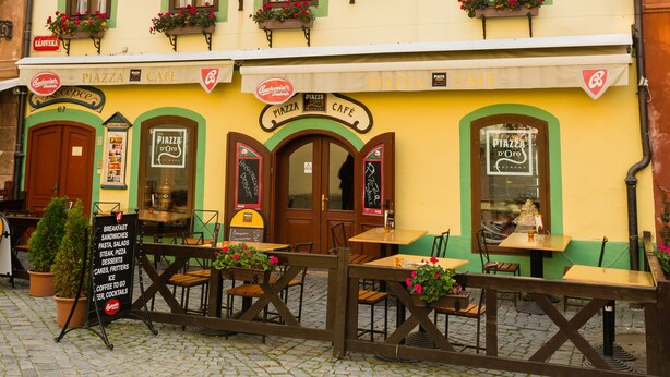 A building with a sign reading "Pension Marie" and "PIZZA CAFE" on the ground floor. There are outdoor tables and chairs in front of the cafe. - Pension Marie (Cesky Krumlov)