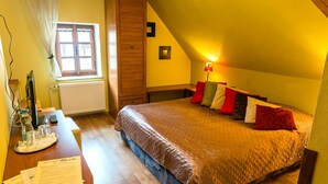 A bedroom with a bed, a desk with papers, a window, and a lamp. - Pension Marie (Cesky Krumlov)