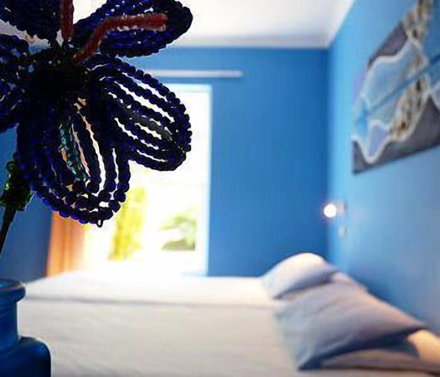 A bedroom with a bed, pillows, and a blue wall.