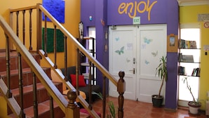 Una escalera conduce a una habitación con una pared morada y un cartel que dice 'enjoy' sobre la puerta.