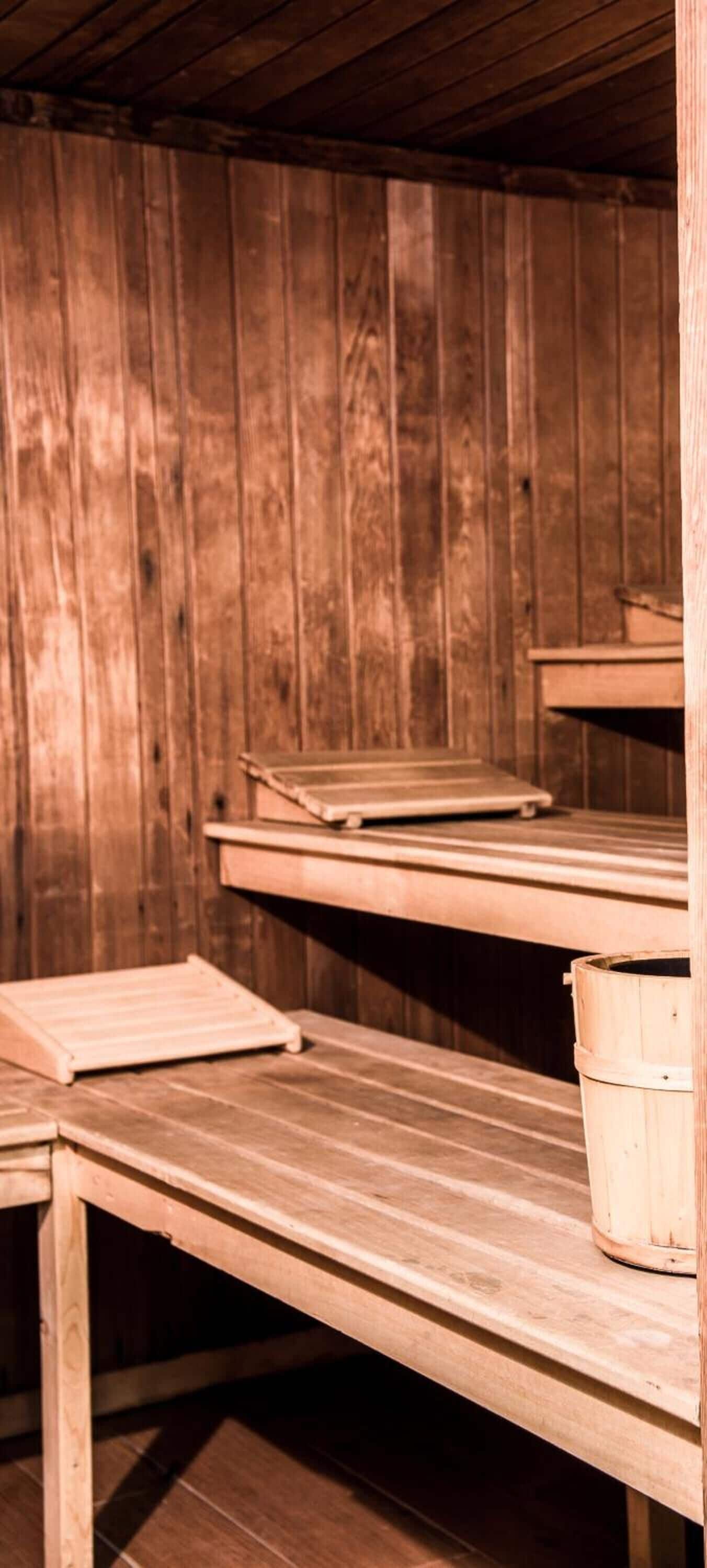 A sauna room with wooden benches and a wooden bucket.