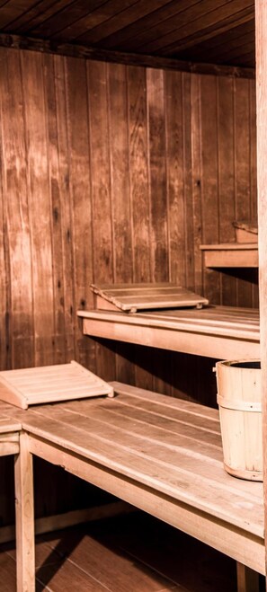 A sauna room with wooden benches and a wooden bucket. - Christiania (La Clusaz)
