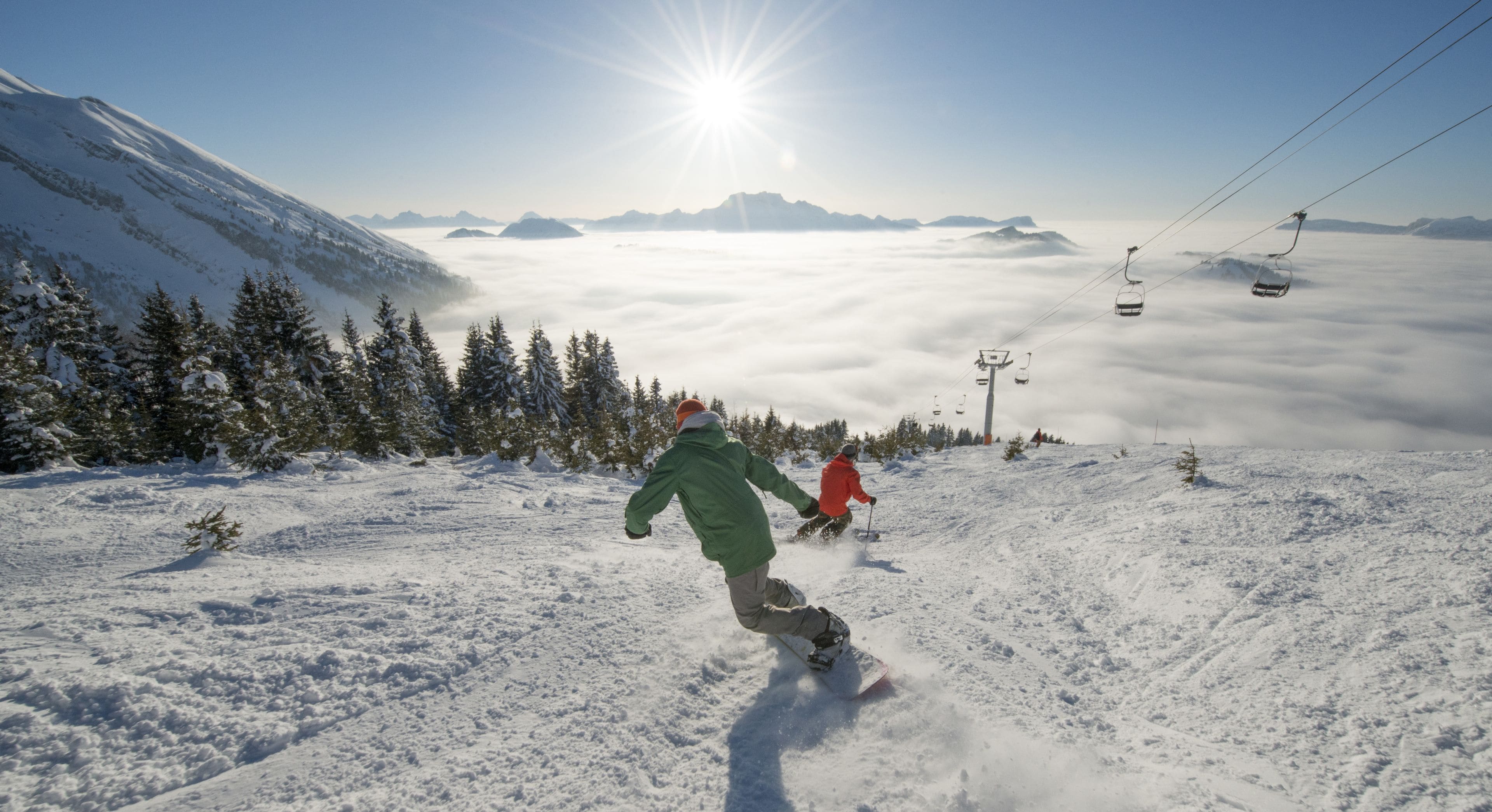 A snowy mountain landscape with a person snowboarding and a ski lift in the background.